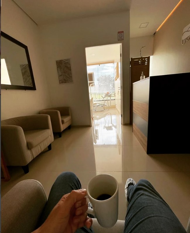 Paciente esperando com um café na sala de espera